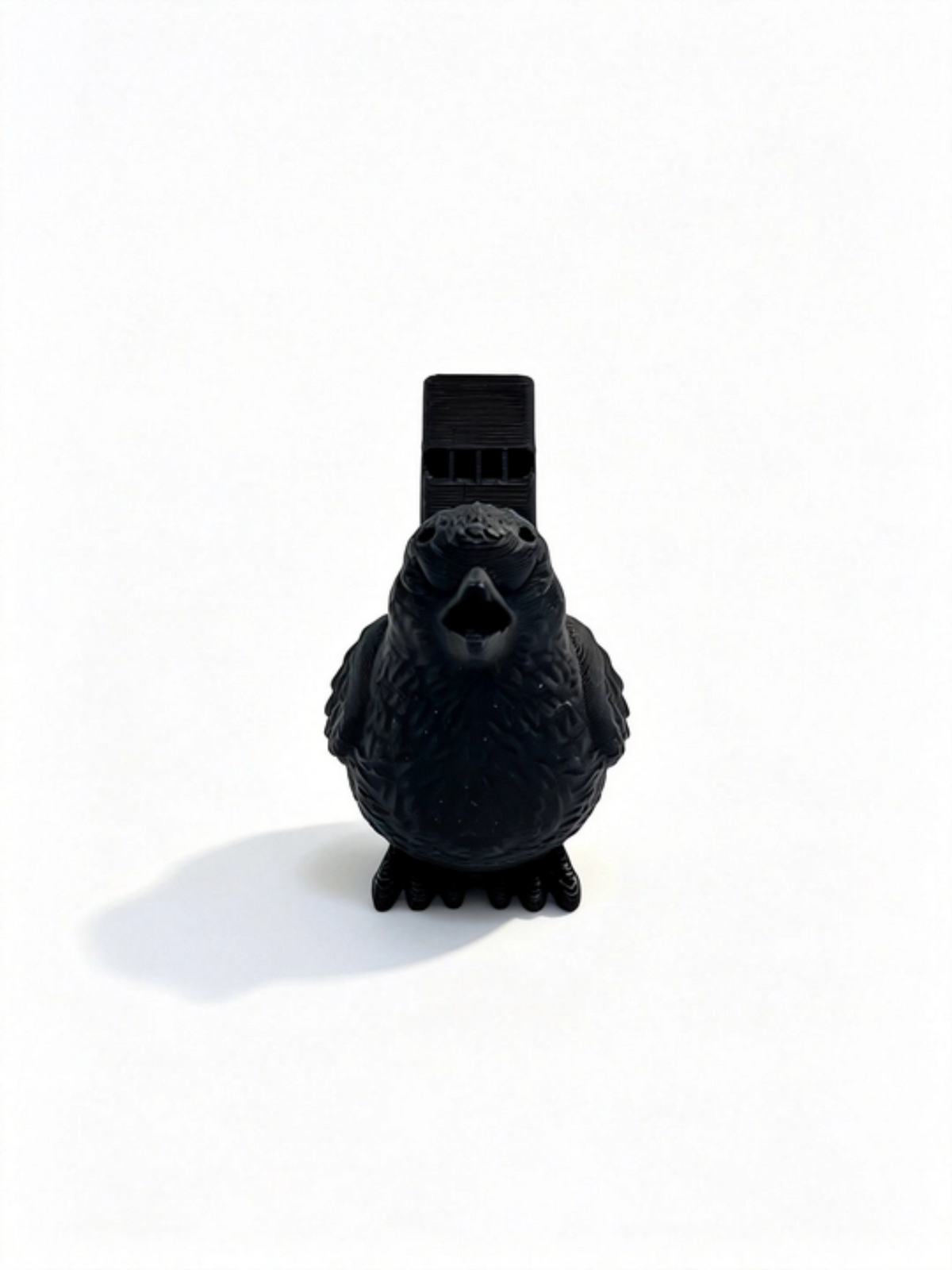 Black bird whistle head-on, open beak with the whistle tube standing behind